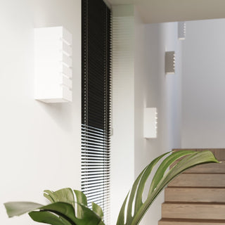 Multiple unlit ceramic wall lamps installed in a modern stairwell, framed by a large green leaf.