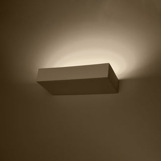 Rectangular ceramic wall lamp mounted on a dark wall, viewed from below, showing the upward light beam.
