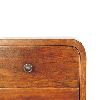 Close view of the rounded top right corner of the chestnut bedside drawer and antique metal knob.