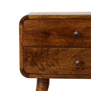 Detail showing the chestnut wood grain, curved front corner, and metal drawer handles.