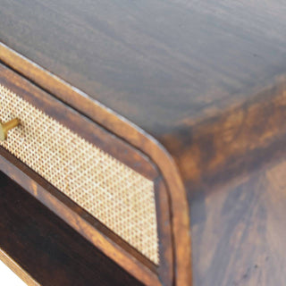 Detail of the chestnut wood bedside showing the smooth top surface meeting the rounded corner and woven drawer.