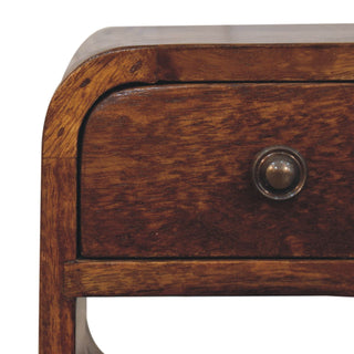 Detail of the dark wood bedside table's rounded top corner and the circular metal drawer knob.