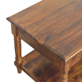 Corner detail of the chestnut coffee table showing the turned leg, lower shelf, and rich wood finish.
