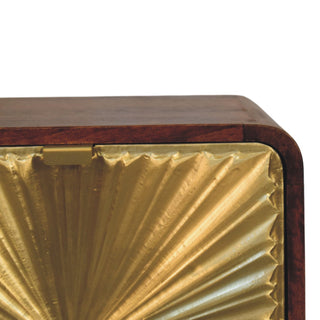 Detail of the brass embossed sunburst drawer front and the rounded corner of the chestnut wood top.