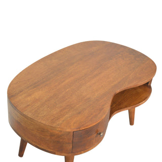 High angle view of the chestnut wave coffee table, showing the kidney shape, wood grain, drawer, and open shelf.