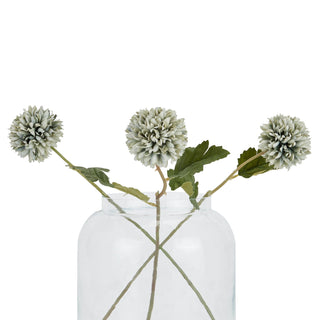 Three pale green blue artificial chrysanthemum stems displayed in a clear glass jar.