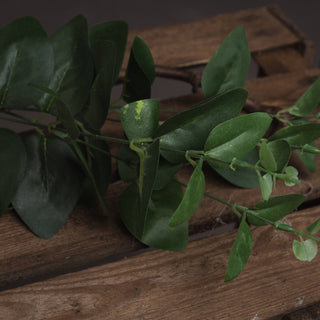 Close up of the artificial eucalyptus spray showing varied green leaves on a dark wooden crate.