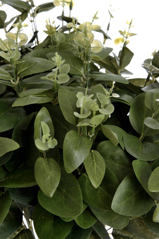 Close up detail of the artificial spray showing light green new growth stems contrasting with dense dark green leaves.
