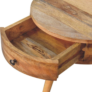 Close-up of the circular bedside table with the drawer pulled open, showing the interior wood grain and bronze knob.