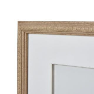 Detail of the beaded wood frame corner, highlighting the light wood grain and white picture mount.