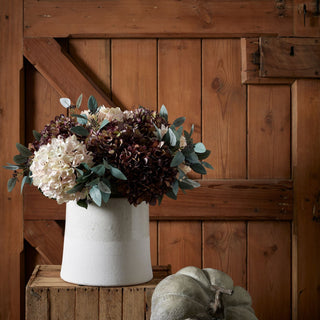 Autumnal bouquet of coffee hydrangeas in a textured grey vase on a wooden crate.