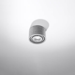 Detailed view of the speckled concrete surface of the ceiling lamp and the recessed light fitting.