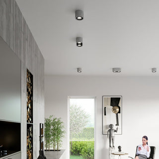 Arrangement of concrete ceiling spotlights installed on a white ceiling in a contemporary open-plan room.