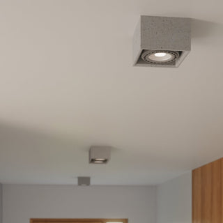 Detail of the rough, speckled grey concrete texture on the ceiling light housing.