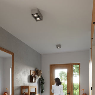 Two concrete ceiling lights, the double and single spot versions, installed in a modern hallway entrance.