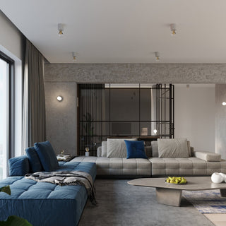 Wide view of a modern flat living space featuring multiple concrete ceiling lights above a blue and grey sofa.