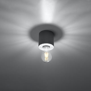 Upward view of the concrete lamp base and exposed filament bulb, highlighting the light pattern on the ceiling surface.