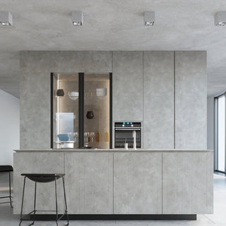 Styled room scene showing four cubic concrete lights mounted on a textured ceiling above a grey kitchen island.