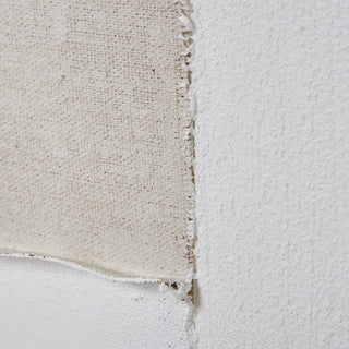 Extreme close-up showing the rough, frayed edge of beige canvas layered over heavily textured white paint.