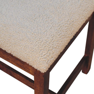 Close up showing the looped texture of the cream boucle seat and the dark wood frame joint.
