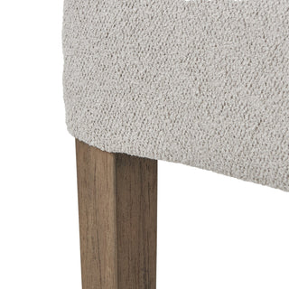 Texture detail of the cream upholstery fabric and the grain of the square wooden leg.