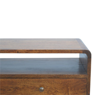 Detail shot showing the curved top edge, open storage shelf, and chestnut drawer with a round metal handle.