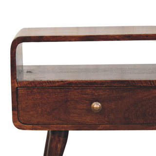 Close-up showing the curved walnut wood corner, open shelf, drawer front, and brass knob detail.