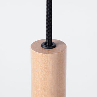 Close detail of the natural wood cylindrical light shade where the black braided cable connects.