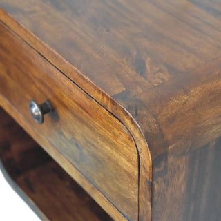 Close-up of the bedside unit's top surface and curved edge, showing the deep sheen and varied wood grain pattern.