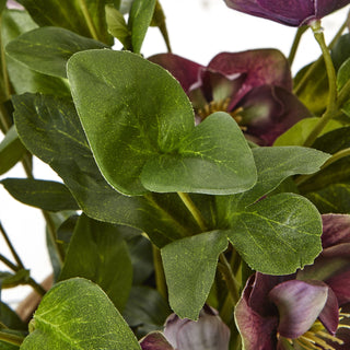 Close detail of the artificial plant showing the fabric texture of the green foliage and plum blooms.