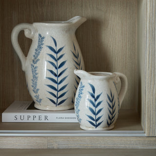 A close-up of the dresser top interior shelf holding two blue and white ceramic jugs and a book.