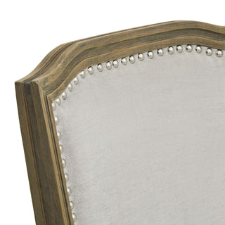 Close-up detail of the chair back showing the distressed wooden frame, grey fabric, and silver nailhead trim.