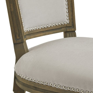 Detail of the seat and backrest joint, showing grey fabric, distressed wood, and silver nailhead trim.