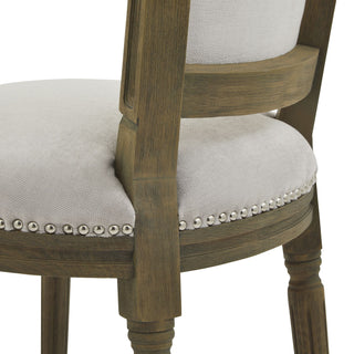Side detail of the grey upholstered seat, highlighting the silver nailhead trim and the texture of the distressed wooden leg.
