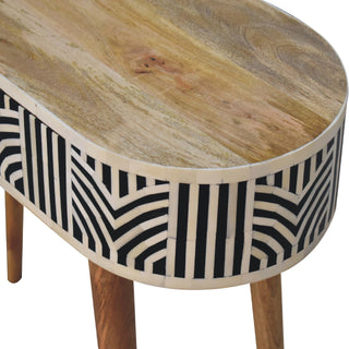 Close-up of the oval console table showing the natural wood grain top and geometric bone inlay side panel.