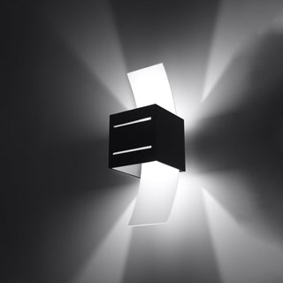Angled view of the black cubic wall light showing the glowing horizontal slits and curved white diffusers.