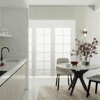 Loreto wall light installed in a bright, minimalist kitchen nook above a round marble dining table.
