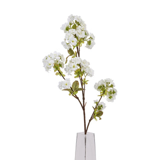 Close up of the artificial white blossom stem showing clusters of flowers and leaves emerging from a clear glass vase base.