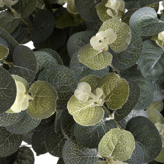 Extreme close-up of artificial eucalyptus leaves in contrasting dark and pale green, featuring small cream flower clusters.