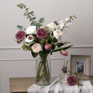 Faux eucalyptus spray used as foliage in a large mixed floral bouquet in a clear glass vase.