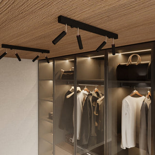 Two black four-spotlight fixtures on a wooden ceiling illuminating the contents of glass wardrobes.