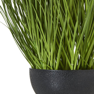 Close view of the textured black pot holding the dense green faux foliage.