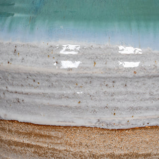 Close detail of the vase texture showing glossy turquoise glaze, textured white band, and rough ceramic base.