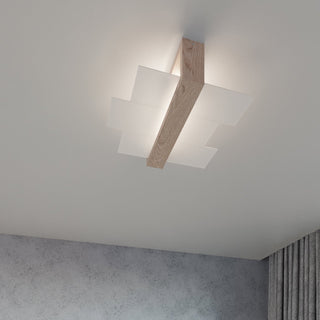 Illuminated ceiling light fixture above a grey textured wall and pleated grey curtains.