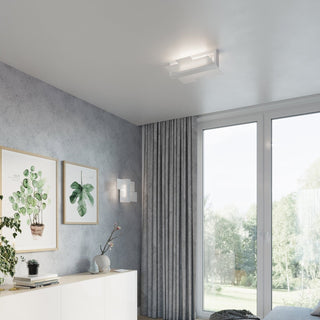 Ceiling light and coordinating wall light illuminating a textured grey wall and white furniture.