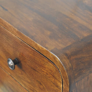 Close view of the rich chestnut finish and rounded corner joint where the top surface meets the drawer front.