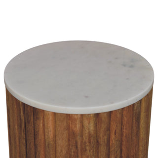 Close-up, top-down view of the round marble surface and the rich brown wooden fluted base.