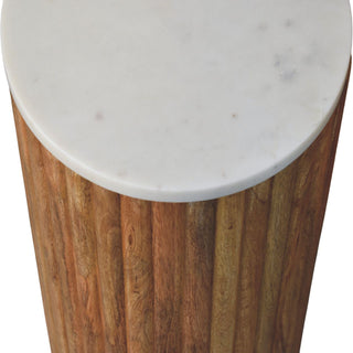 Close detail of the white marble tabletop edge meeting the vertical fluting of the rich brown wooden base.