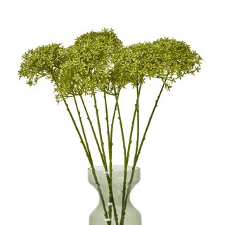 Seven artificial green stems displayed in a translucent green glass vase.