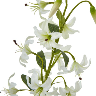 Detailed view of the artificial lily spray showing the white petals, green foliage, and dark stamens.